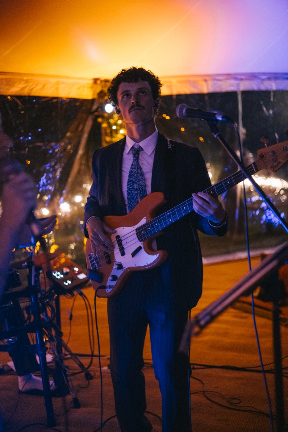 George in a suit playing a sunburst bass guitar